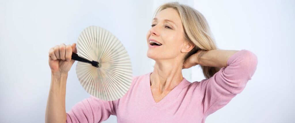 Dojrzała kobieta doświadcza uderzeń gorąca i wachluje się wachlarzem