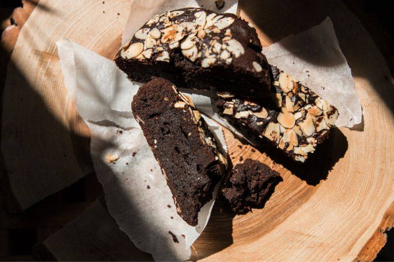 Pokrojone kawałki ciasto czekoladowego zaprezentowane na drewnianej desce i papierze do pieczenia.
