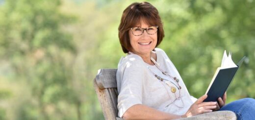 Uśmiechnięta dojrzała kobieta czyta książkę na leżaku