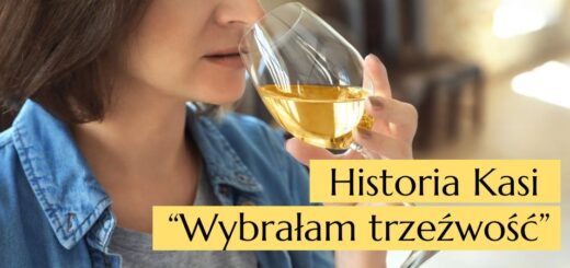Kobieta pijąca trzyma w dłoni kieliszek białego wina i zbliża go do ust